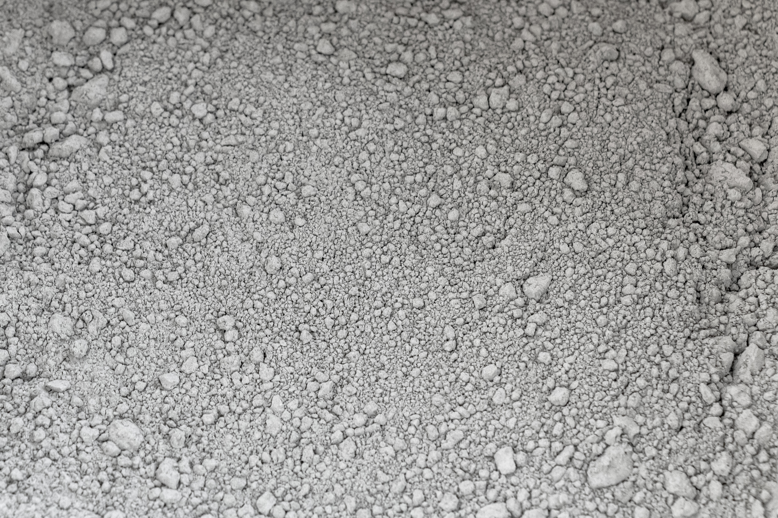 Close-up of loose gray cement powder and small clumps, photographed at the Weisenau cement plant; no brand/package visible.